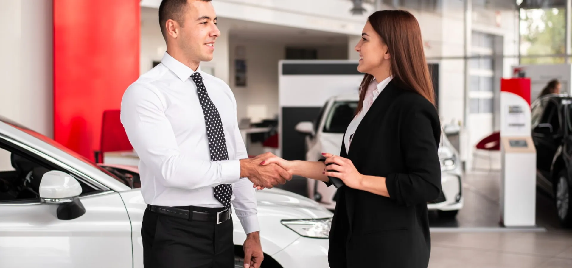 Man and woman shake hands on a successfully sold car
