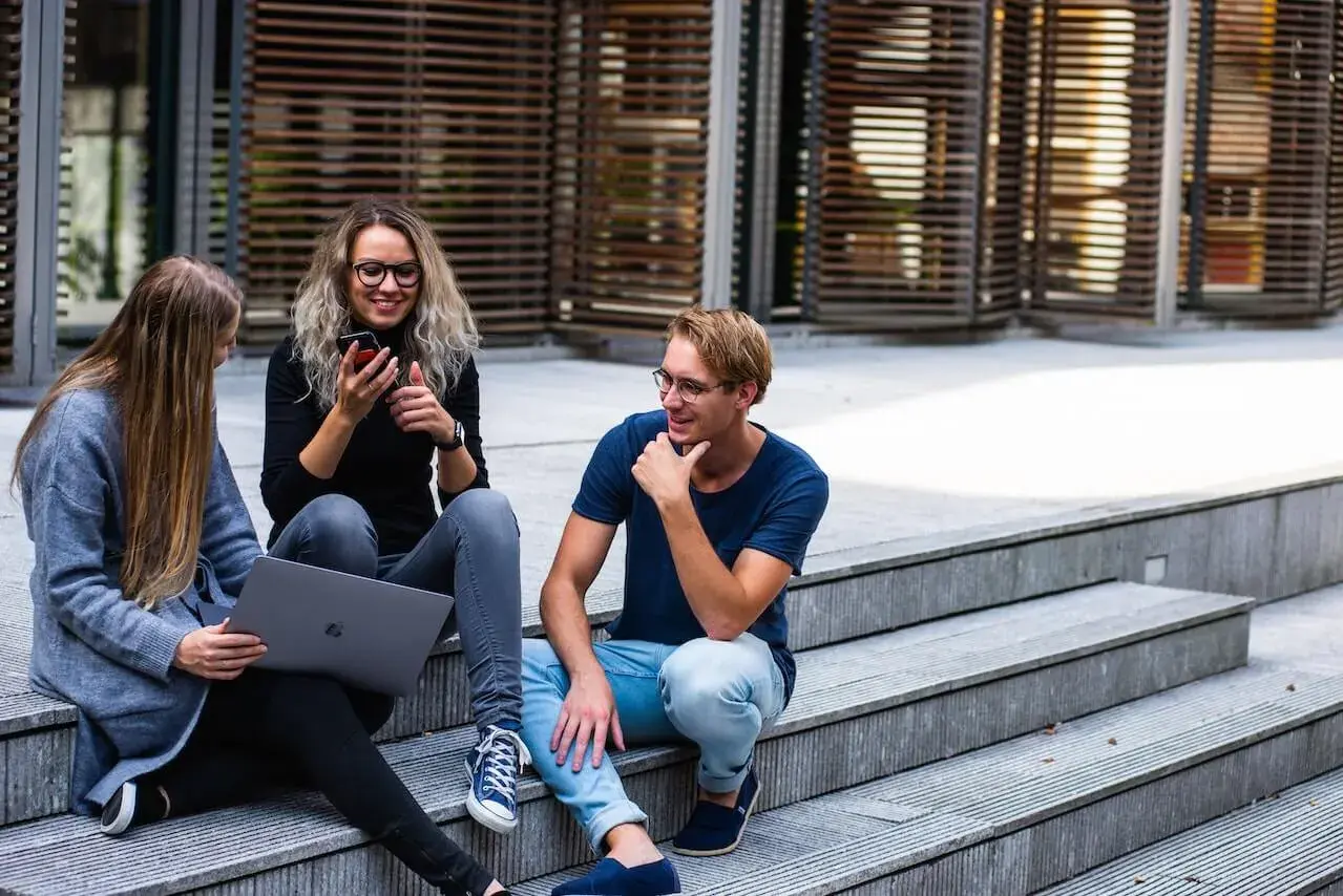 Students sitting on stairs in front of the college, talking and laughing Students sitting on stairs in front of the college, talking and laughing