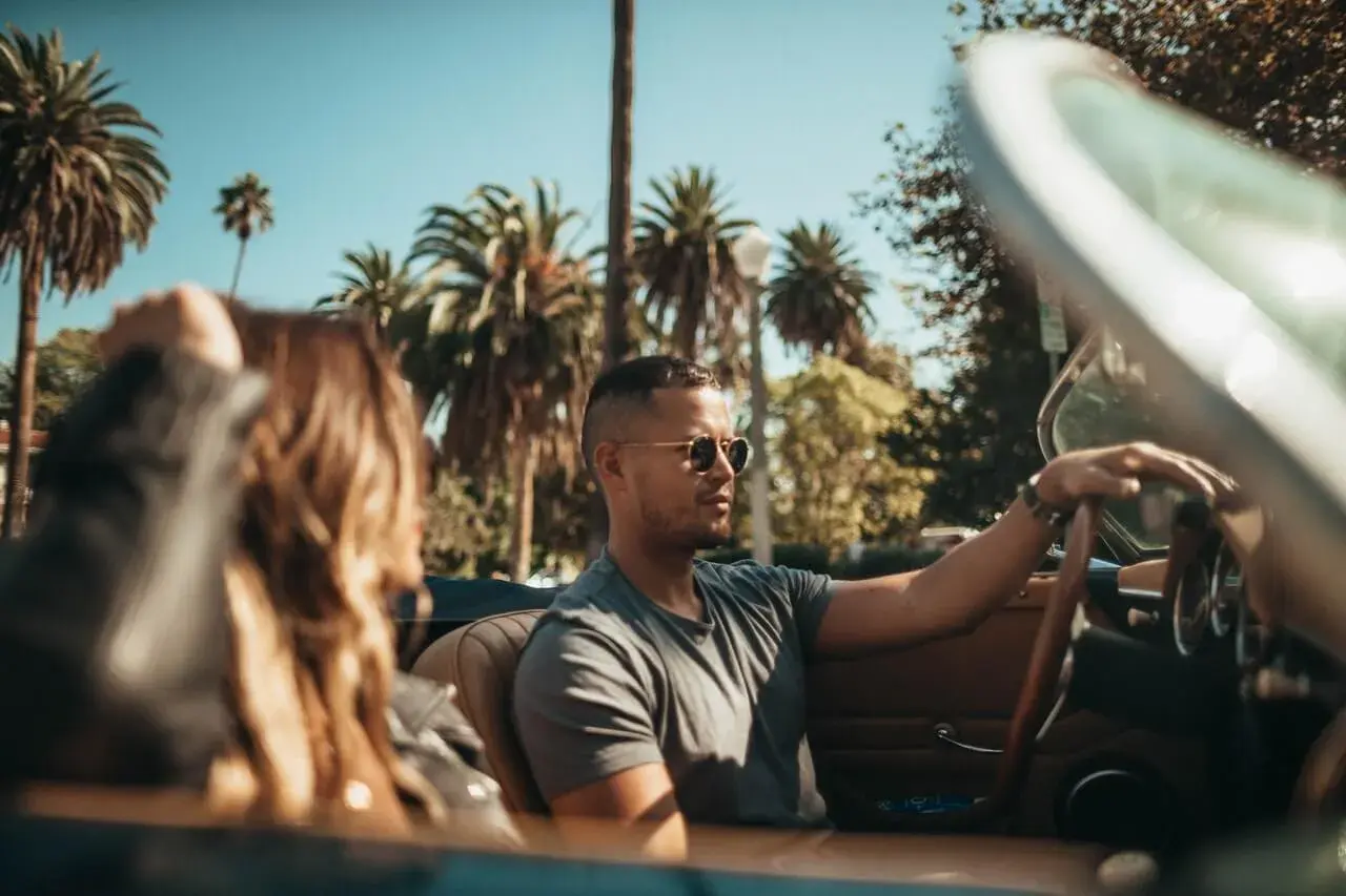 a man and woman riding a convertible car a man and woman riding a convertible car