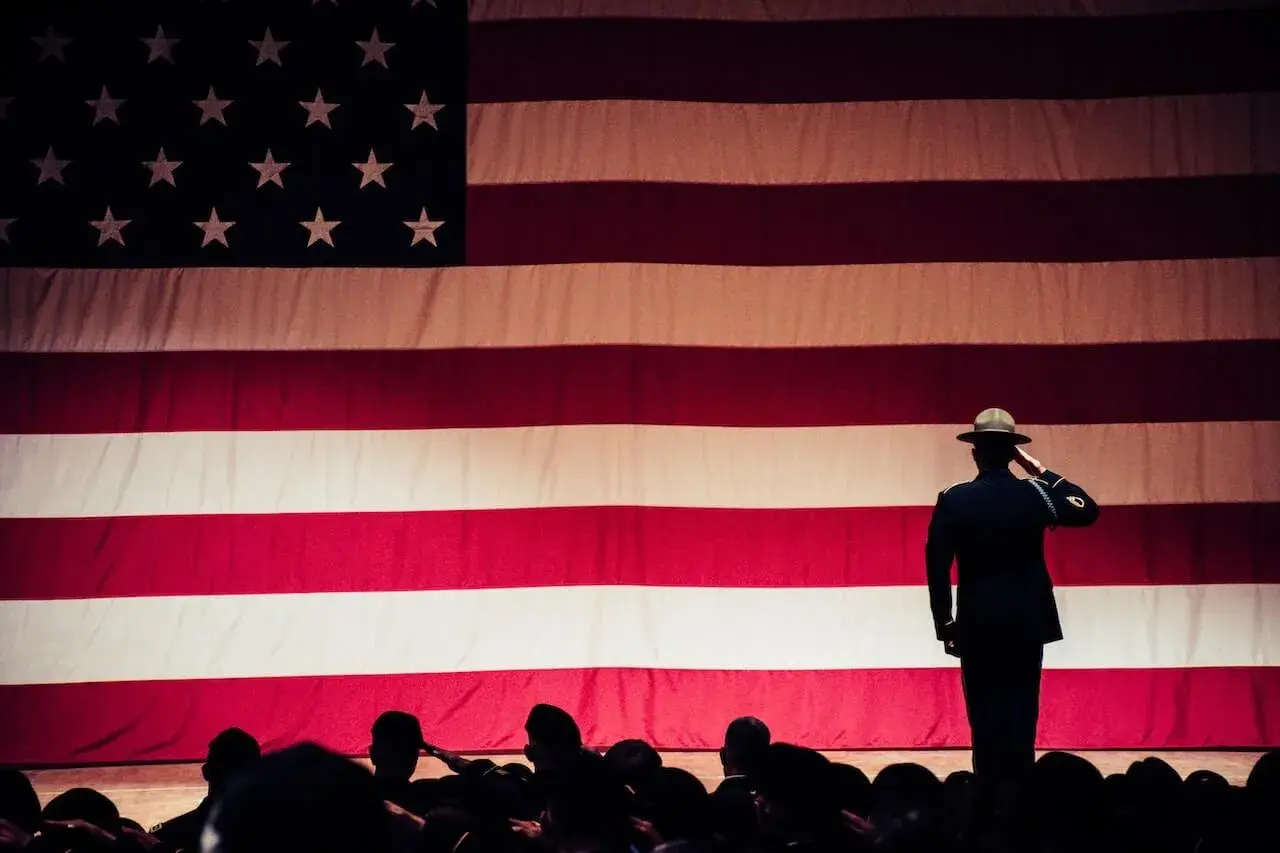 A soldier standing in front of the American flag A soldier standing in front of the American flag