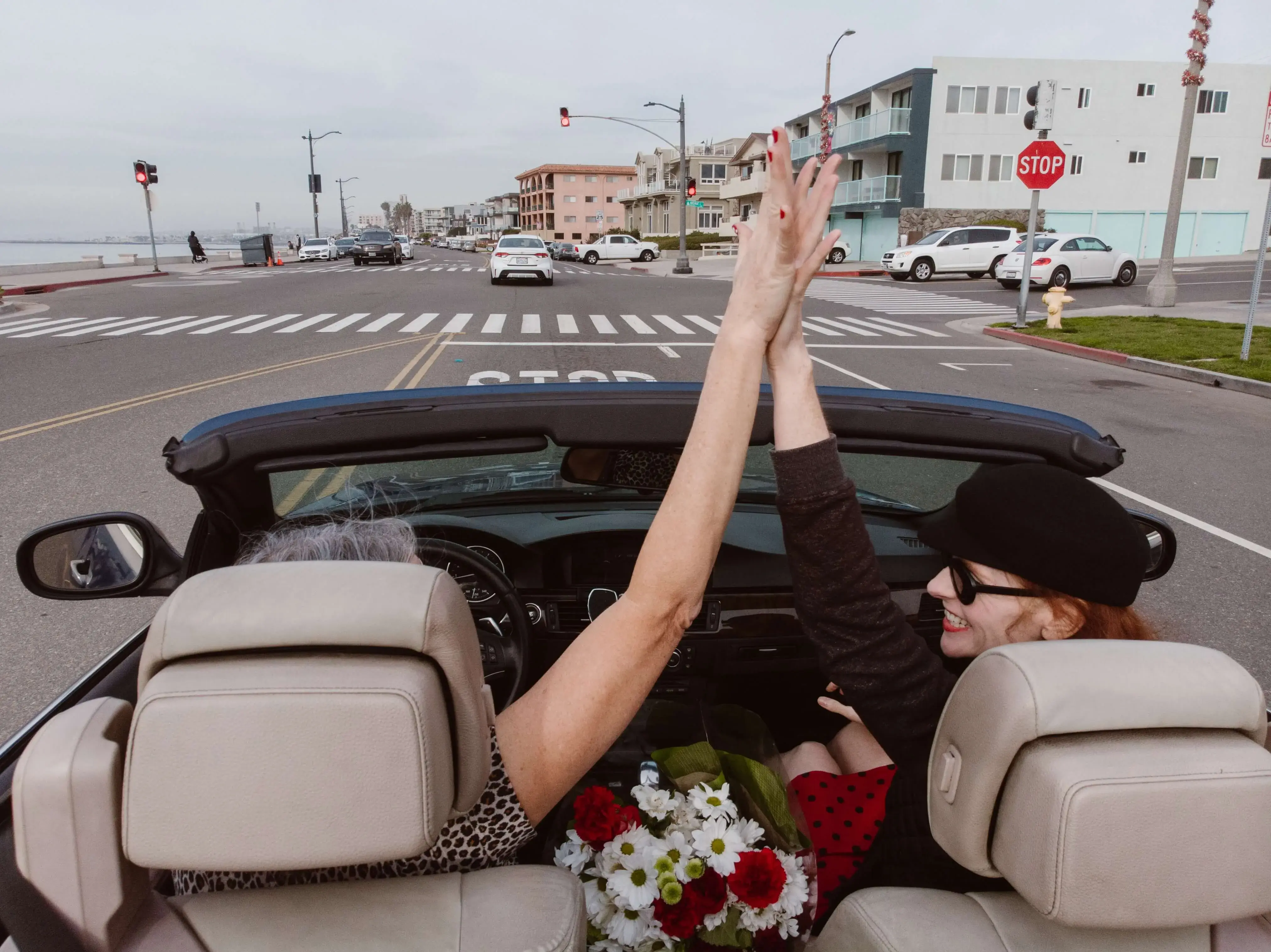 Two women giving high five in a convertible vehicle in California Two women giving high five in a convertible vehicle in California