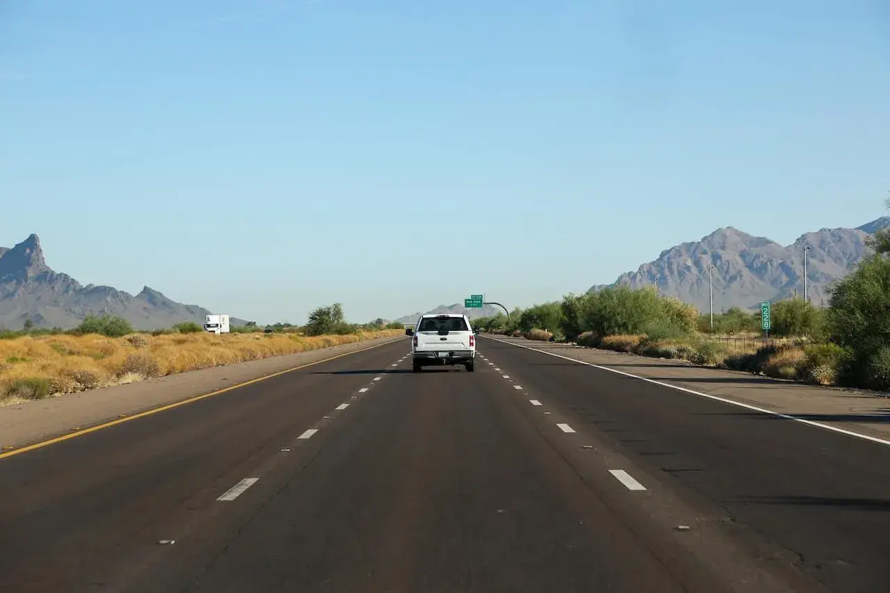Car riding on asphalt road between meadows and mountain ranges Car riding on asphalt road between meadows and mountain ranges